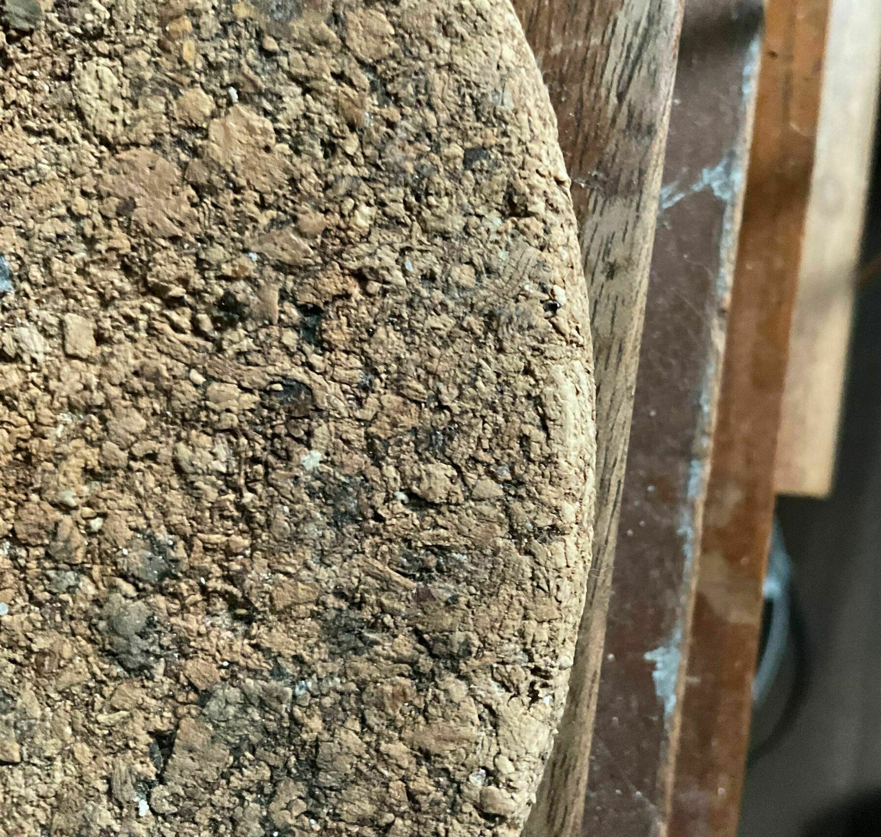 view towards floor of a round cork mat on the edge of a desk with the edges of desk drawers visible.